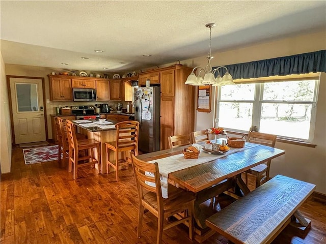 dining area featuring a chandelier, dark wood-type flooring, recessed lighting, and a textured ceiling