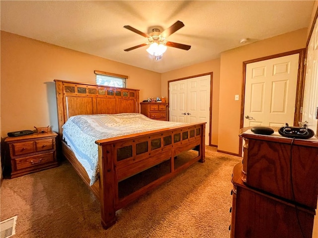 bedroom featuring dark carpet, ceiling fan, and a closet