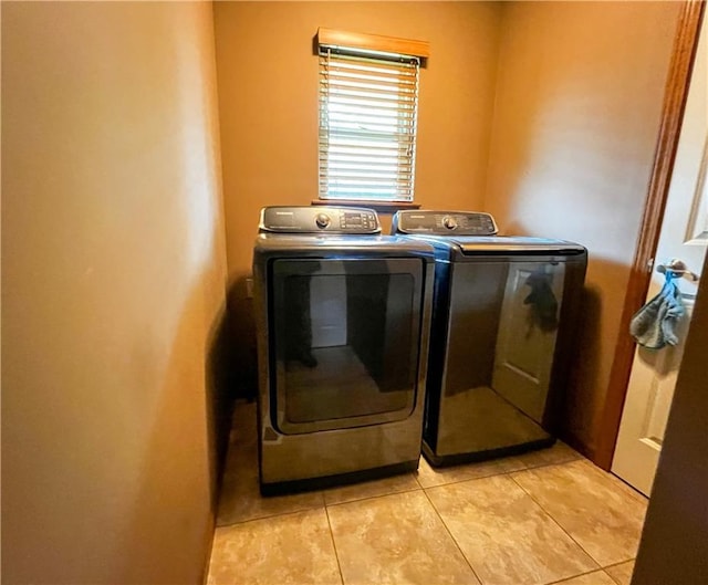 laundry area with washer and clothes dryer and light tile patterned floors