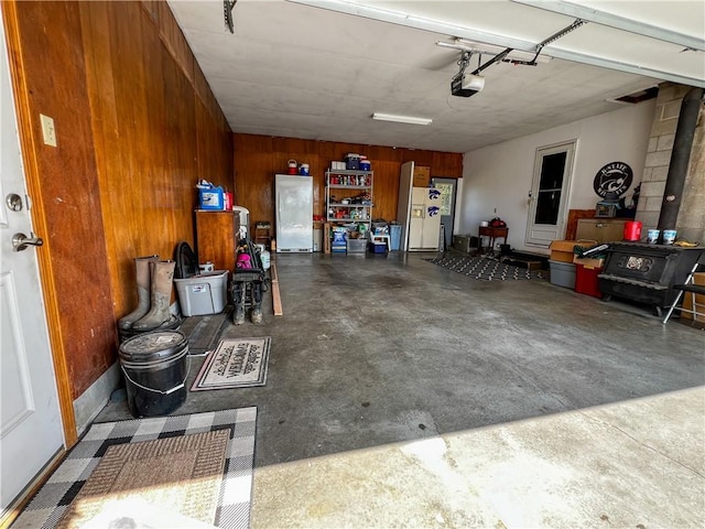 garage featuring a wood stove, wood walls, and a garage door opener