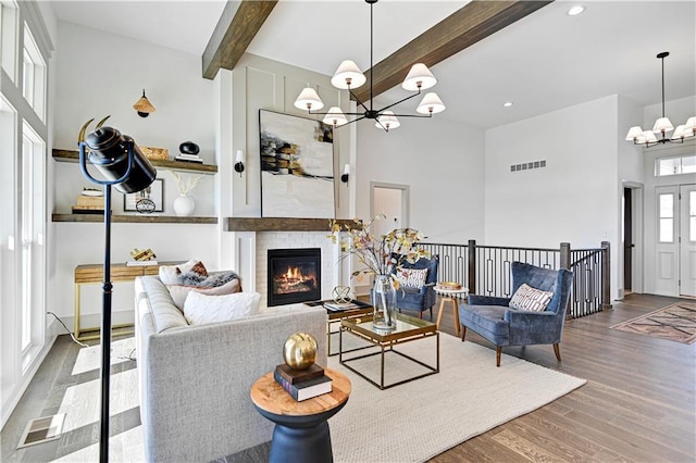 13485 W 174th Pl, Overland Park, KS 66221 - living room with a chandelier, beam ceiling, wood finished floors, a high ceiling, and a glass covered fireplace