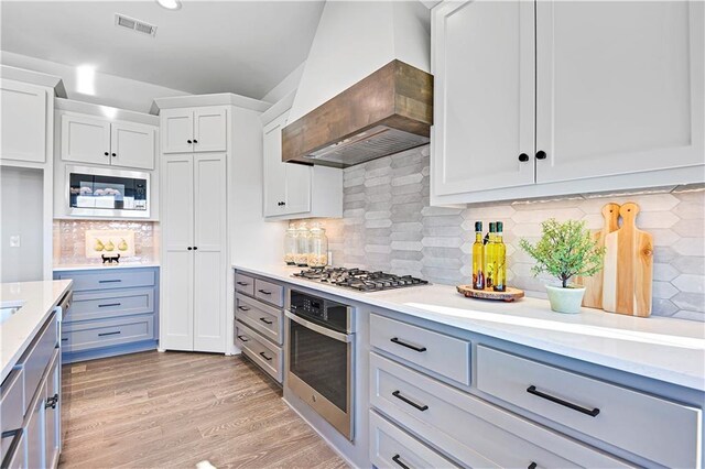 13485 W 174th Pl, Overland Park, KS 66221 - kitchen with stainless steel appliances, custom exhaust hood, light countertops, tasteful backsplash, and white cabinets