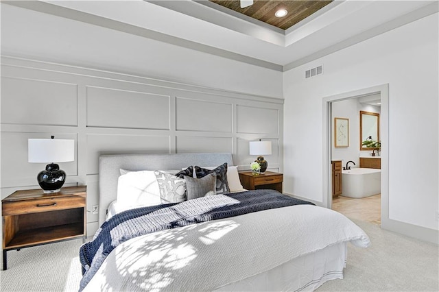 13485 W 174th Pl, Overland Park, KS 66221 - bedroom featuring a decorative wall, a tray ceiling, light colored carpet, and ensuite bath