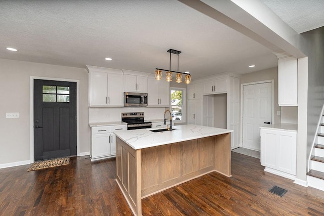 kitchen with dark wood-type flooring, an island with sink, white cabinets, stainless steel appliances, and sink