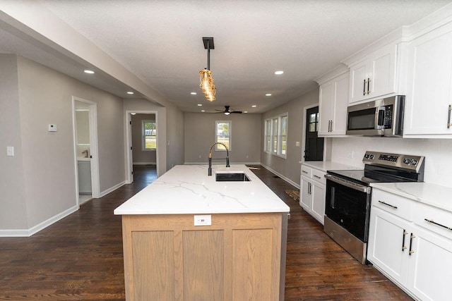 kitchen with white cabinets, pendant lighting, stainless steel appliances, a center island with sink, and sink