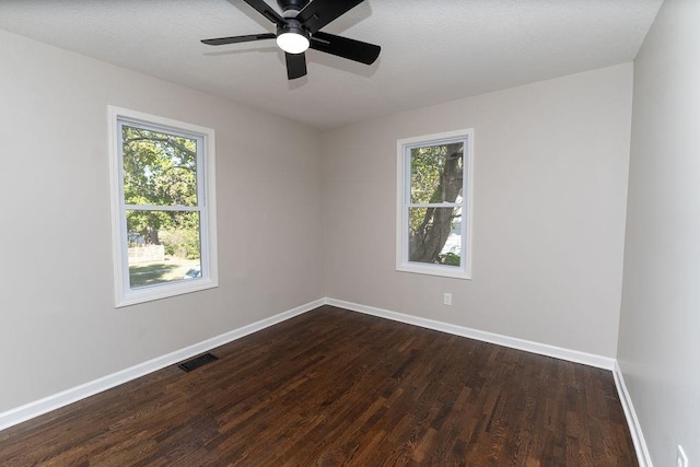 empty room with a wealth of natural light, ceiling fan, and dark hardwood / wood-style flooring