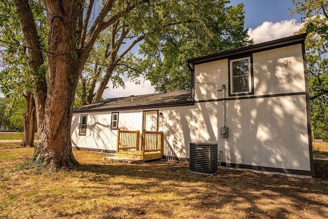 rear view of house featuring a deck, a yard, and central AC