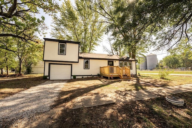 rear view of house featuring a garage and a wooden deck