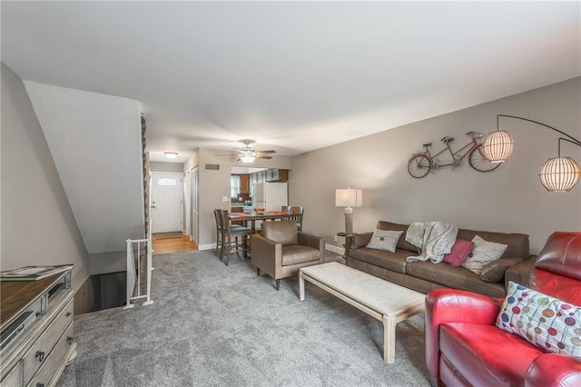 carpeted living room with a ceiling fan and baseboards