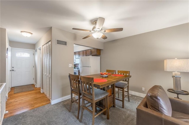 dining area featuring light carpet, baseboards, visible vents, and a ceiling fan