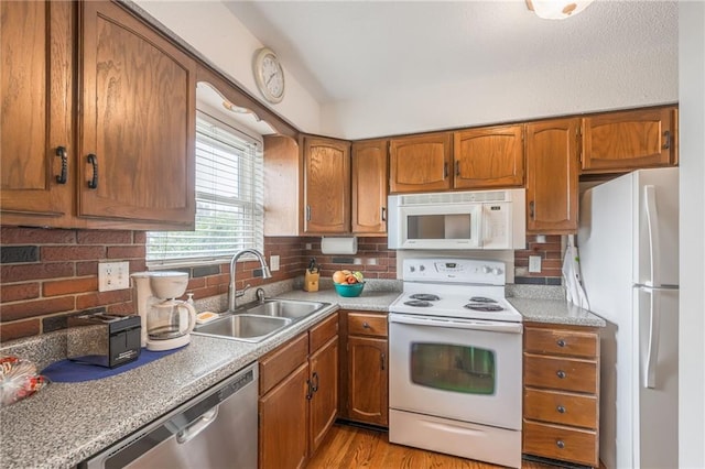 kitchen with white appliances, tasteful backsplash, brown cabinets, and a sink