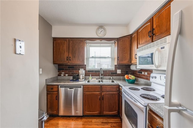 kitchen with white appliances, wood finished floors, a sink, light countertops, and backsplash