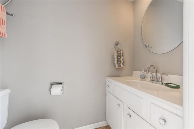 bathroom featuring toilet, baseboards, and vanity