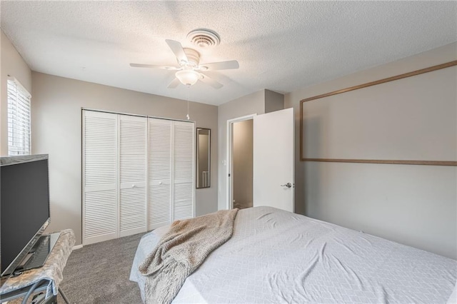 carpeted bedroom with visible vents, a closet, a ceiling fan, and a textured ceiling