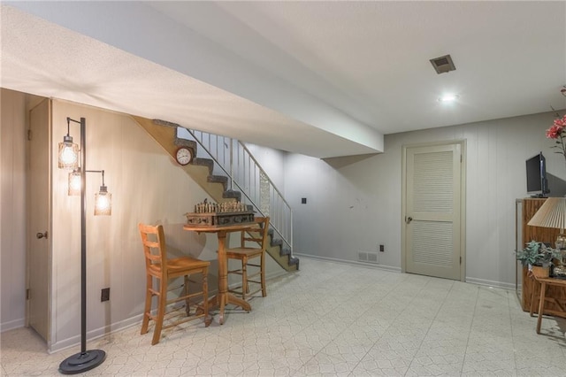 finished below grade area featuring baseboards, stairs, visible vents, and tile patterned floors