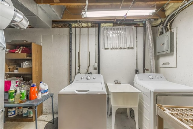 washroom featuring laundry area, electric panel, washer and clothes dryer, and a sink