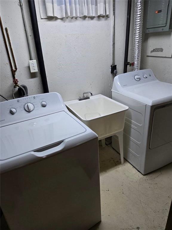 laundry room with laundry area, electric panel, washer and dryer, and a sink