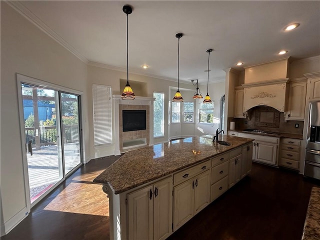 kitchen with pendant lighting, an island with sink, a fireplace, and dark hardwood / wood-style flooring