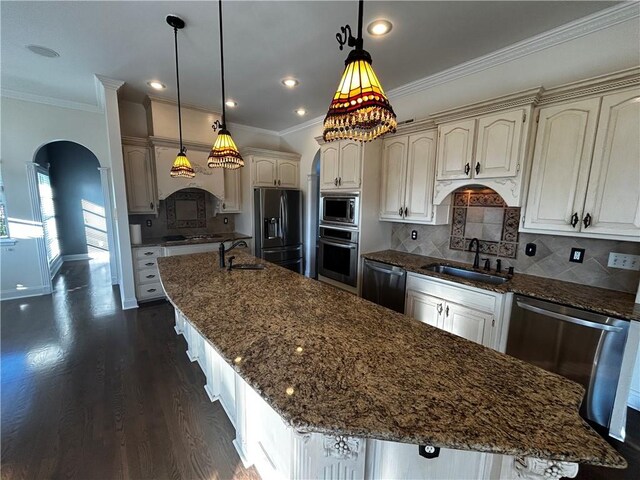 kitchen featuring pendant lighting, a kitchen island with sink, sink, appliances with stainless steel finishes, and dark hardwood / wood-style flooring