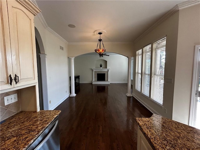 interior space with a tile fireplace, crown molding, decorative columns, and dark wood-type flooring