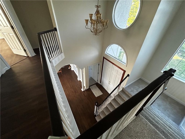 stairs with a notable chandelier, hardwood / wood-style floors, and a high ceiling