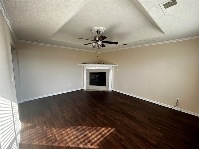 unfurnished living room with a textured ceiling, dark wood-type flooring, a tiled fireplace, crown molding, and ceiling fan