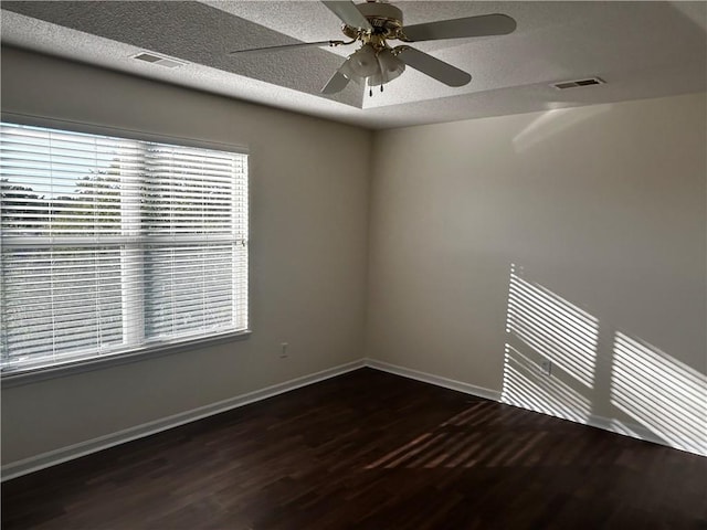 empty room featuring ceiling fan, a textured ceiling, and dark wood-type flooring