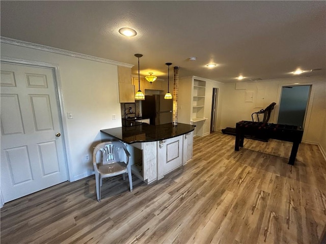 kitchen with hanging light fixtures, a breakfast bar, kitchen peninsula, white fridge, and hardwood / wood-style flooring