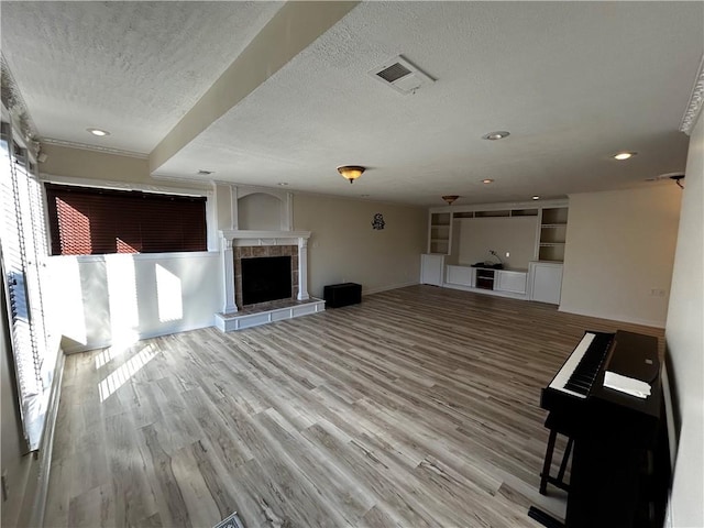 unfurnished living room with wood-type flooring, a textured ceiling, and a fireplace