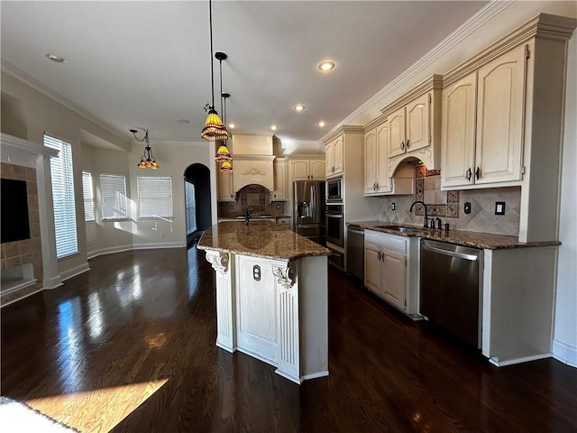 kitchen with hanging light fixtures, sink, stainless steel appliances, dark hardwood / wood-style floors, and dark stone counters