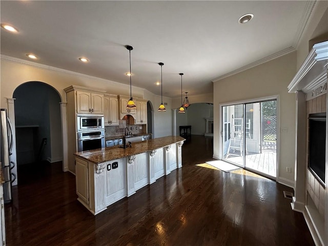 kitchen with hanging light fixtures, appliances with stainless steel finishes, dark hardwood / wood-style floors, a center island, and dark stone countertops