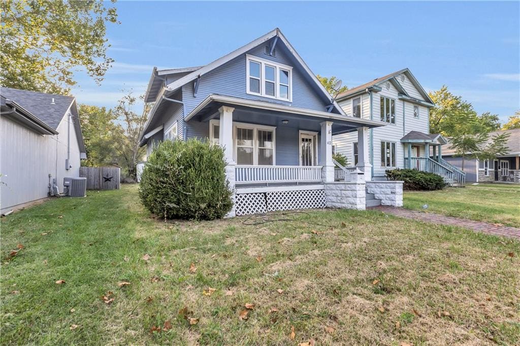 view of front of house featuring cooling unit, a front lawn, and a porch