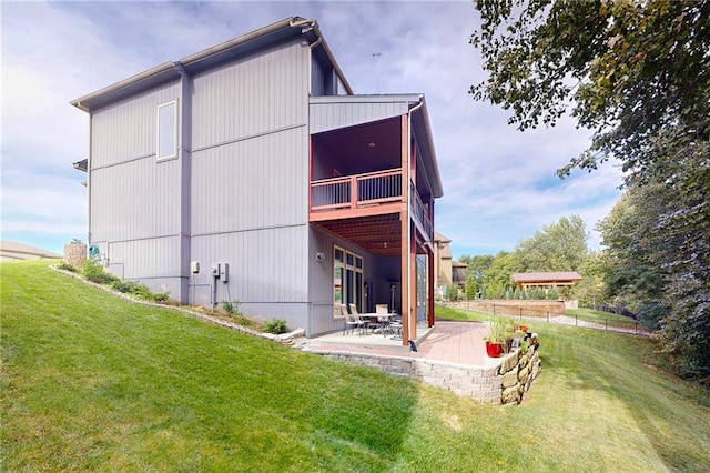 back of property featuring a balcony, a lawn, and a patio area