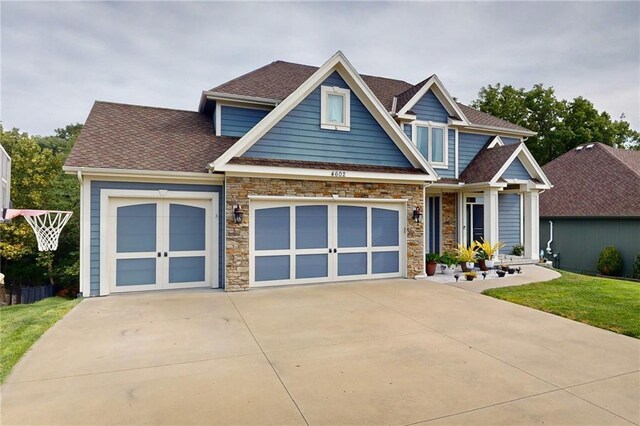 4602 NW Verona Dr, Riverside, MO 64150 - craftsman-style house with stone siding, driveway, a shingled roof, an attached garage, and a front yard