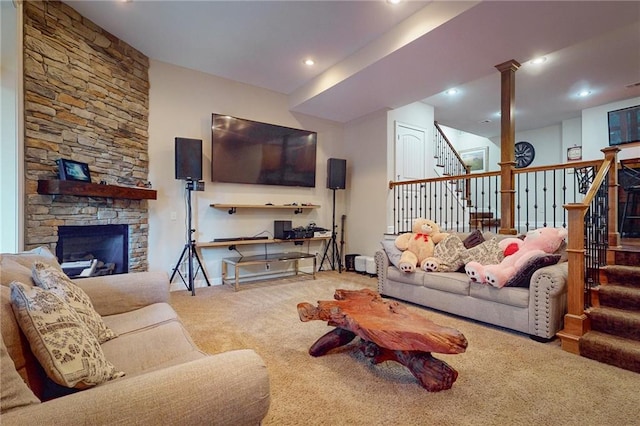 carpeted living room with decorative columns and a stone fireplace