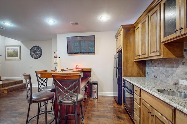 kitchen featuring light stone counters, dark hardwood / wood-style flooring, tasteful backsplash, and black appliances