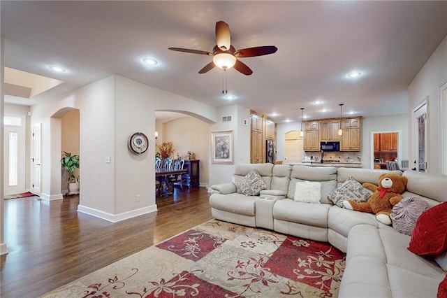 living room with ceiling fan and dark hardwood / wood-style flooring