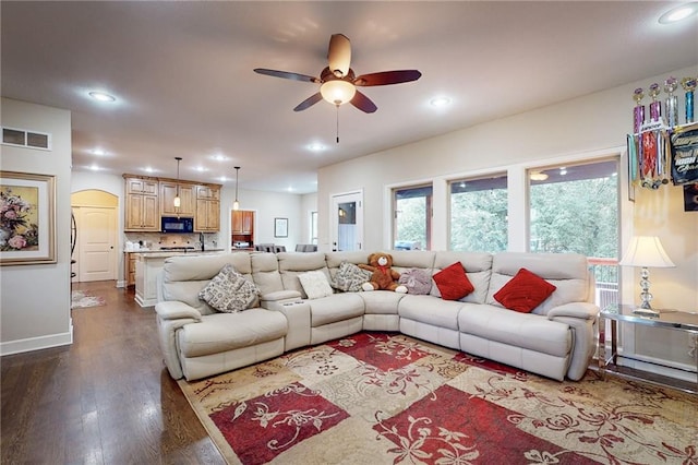 living room featuring dark wood-type flooring and ceiling fan