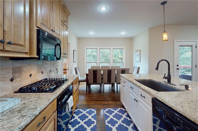 kitchen with light stone counters, dark wood-type flooring, sink, backsplash, and black appliances