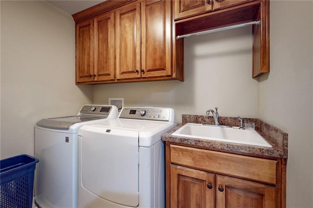 clothes washing area with washer and clothes dryer, sink, and cabinets