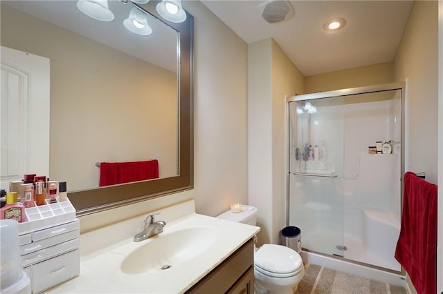 bathroom featuring vanity, a shower with shower door, and toilet