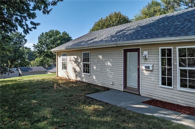 exterior space featuring a yard and a shingled roof