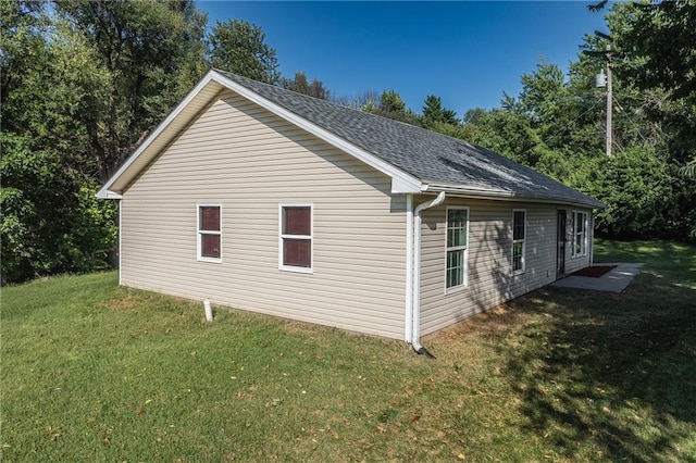 view of side of property with a yard and roof with shingles