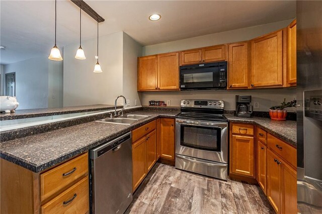 kitchen with a peninsula, brown cabinets, appliances with stainless steel finishes, and a sink