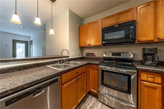 kitchen featuring a sink, stainless steel appliances, brown cabinets, and hanging light fixtures