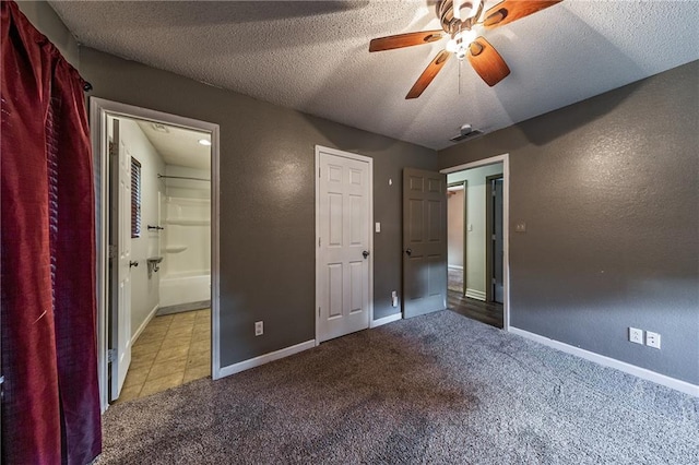 unfurnished bedroom featuring carpet flooring, a textured ceiling, ensuite bathroom, and baseboards