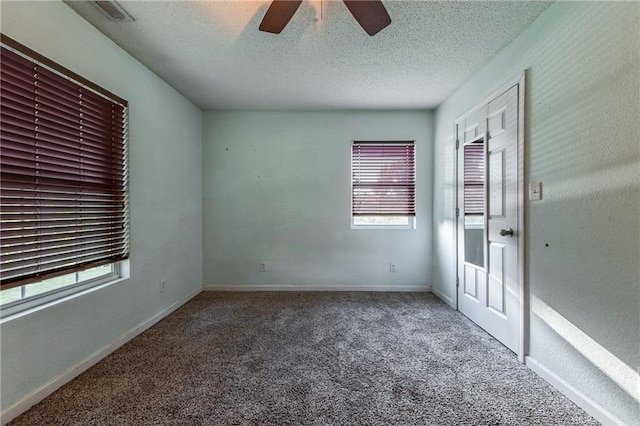 carpeted spare room featuring baseboards, visible vents, a textured ceiling, and ceiling fan