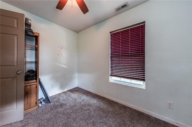 empty room with carpet, baseboards, visible vents, ceiling fan, and a textured ceiling