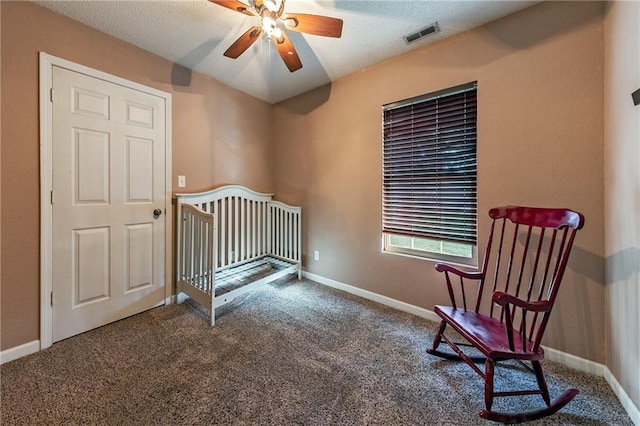 bedroom featuring visible vents, baseboards, carpet floors, a ceiling fan, and a nursery area