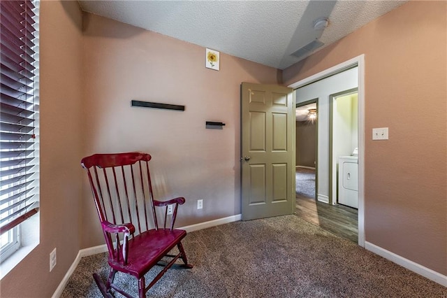 living area featuring carpet flooring, a textured ceiling, washer / clothes dryer, and baseboards